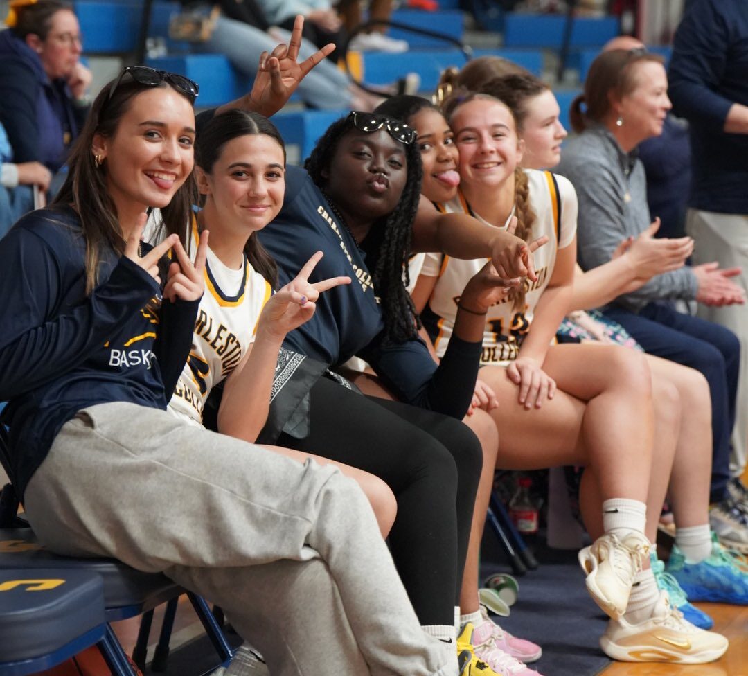 Varsity girls basketball players on the bench during a game.