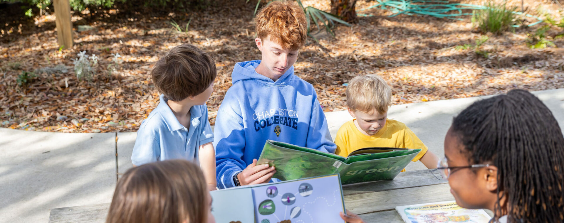 Upper School students read to Lower School students outside. 
