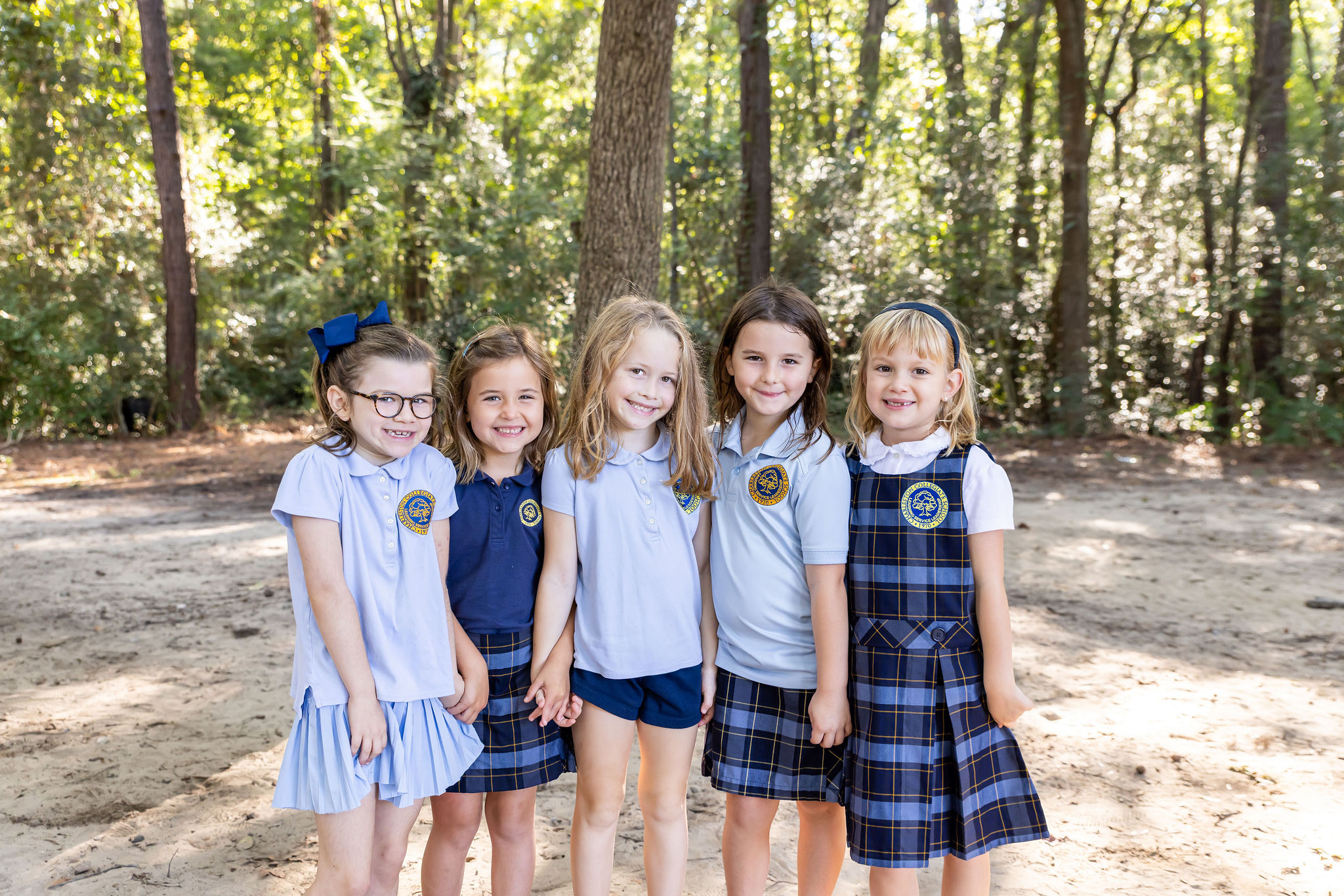 A group of younger students smiling outside on campus.