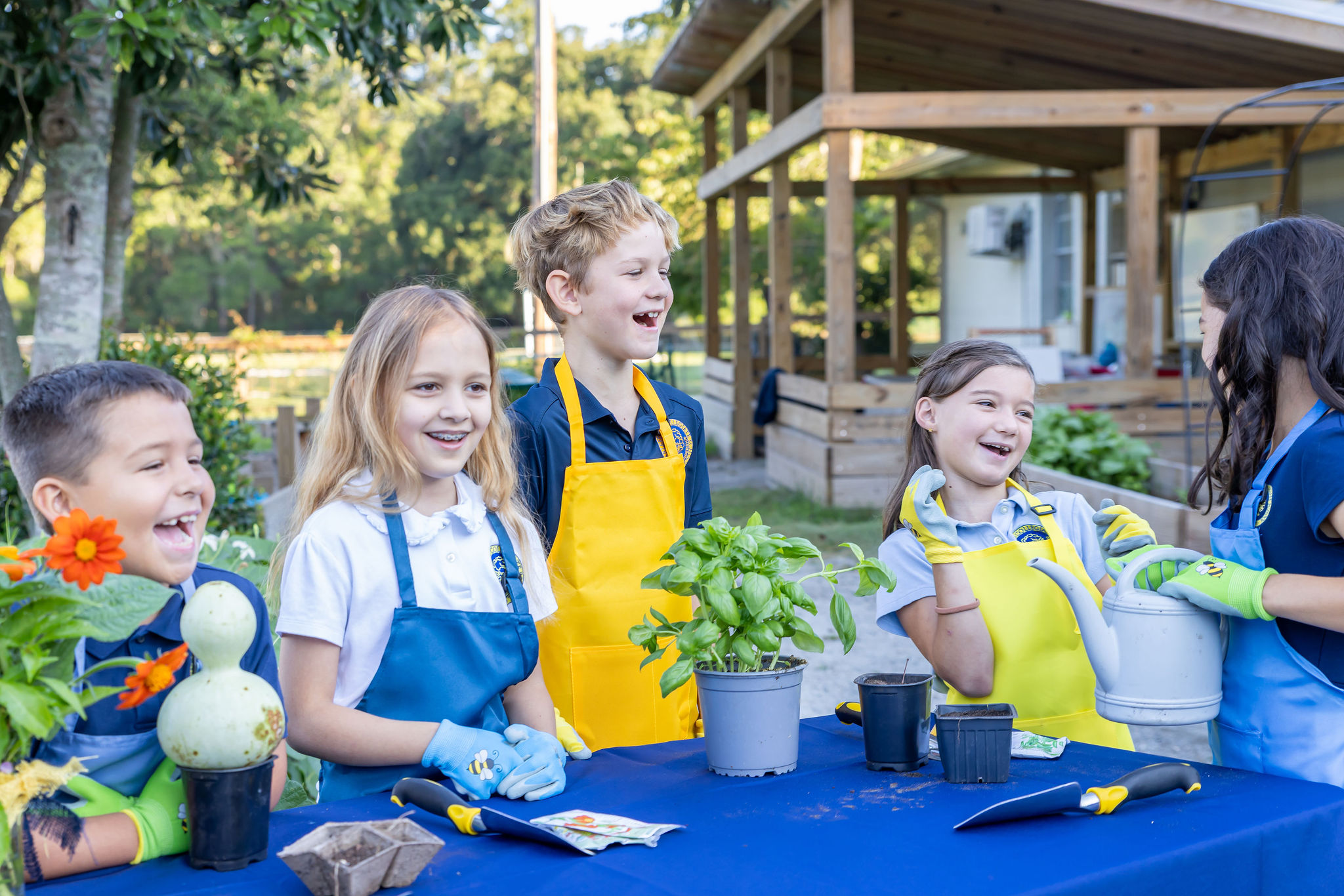 A group of young students smiling with plants from their garden.