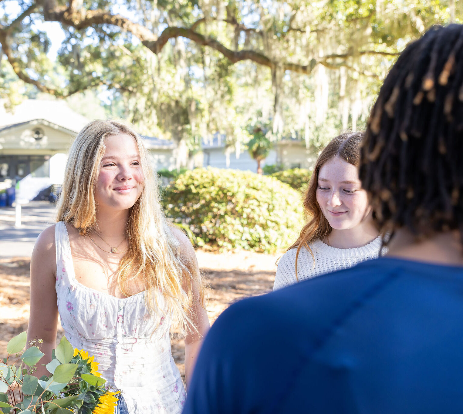 A student smiling while talking to a group of friends outside on campus.
