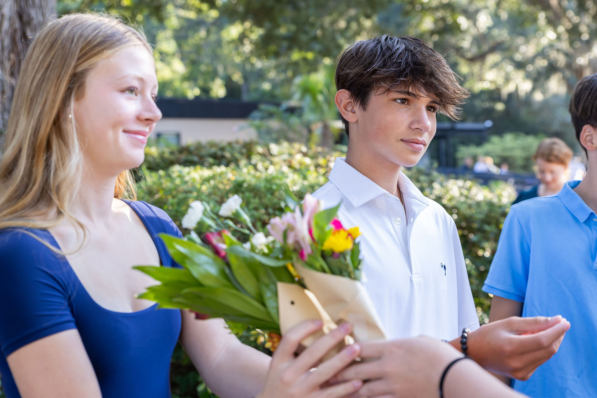 A smiling student holding a bouquet of flowers.