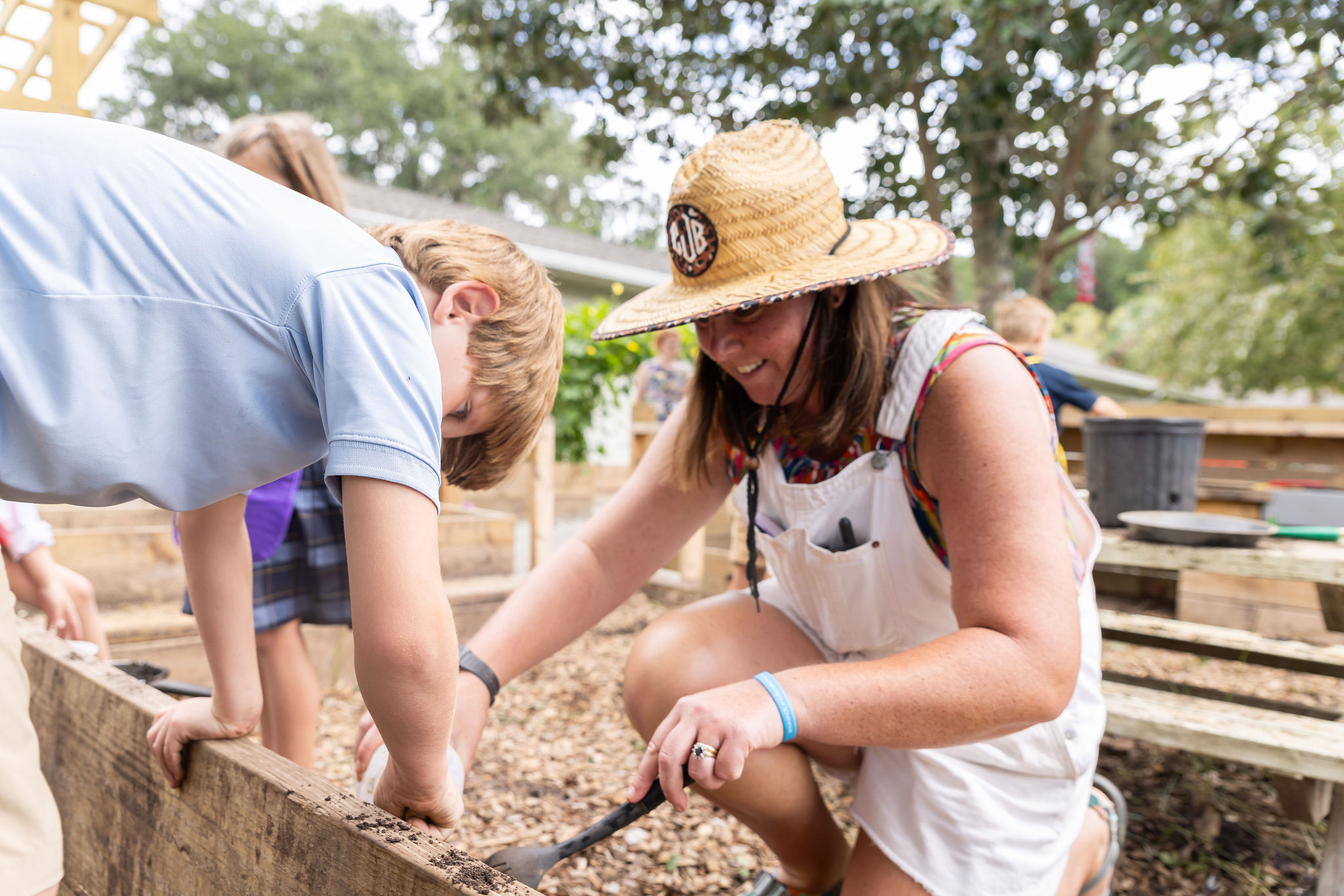 Lower school CCS outdoor education teacher shows students best practices in the garden.