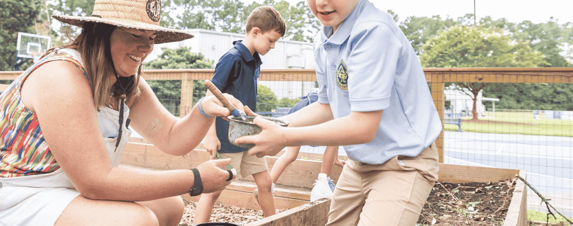 A teacher and young students working in the garden.