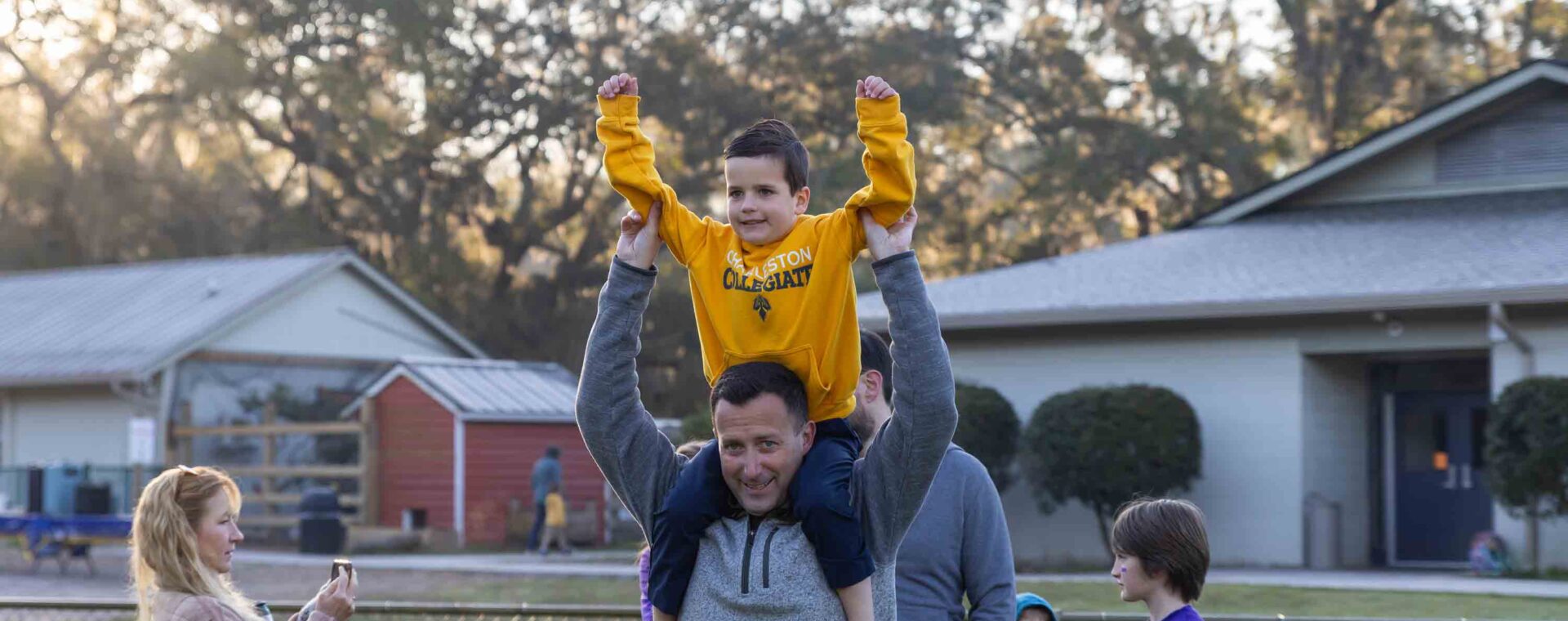 Student celebrates on parents shoulders.